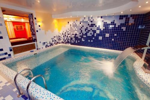 un jacuzzi en un baño con azulejos azules en AMAKS Premier Hotel, en Perm