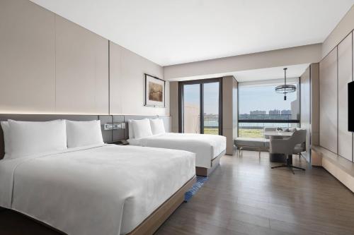 a hotel room with two beds and a desk at JW Marriott Shanghai Fengxian in Shanghai