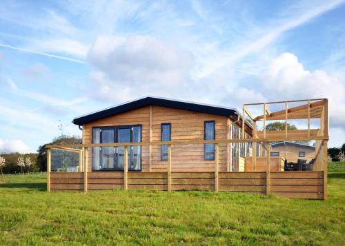 a wooden house with a large deck in a field at Cherry Bird Country Park in Newbury
