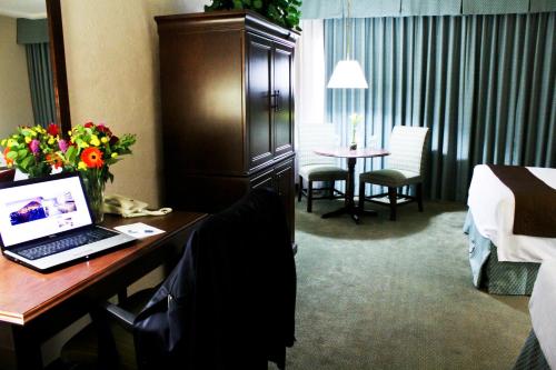 um quarto de hotel com uma secretária com um computador portátil em University Square Hotel em Fresno