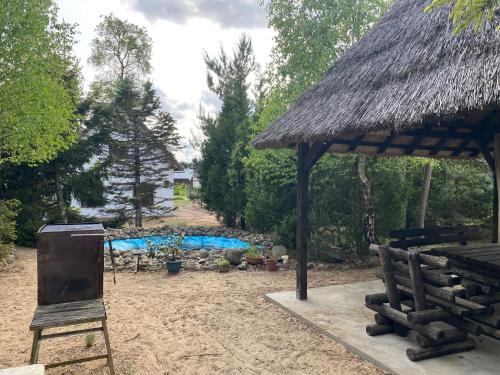 a straw hut with a chair and a table and a chair at Domek Bory Tucholskie in Skorka