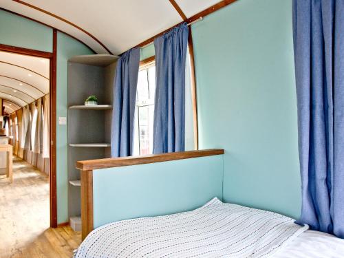 a bedroom with blue walls and a bed with blue curtains at Brunel Boutique Railway Carriage 5 in Dawlish Warren