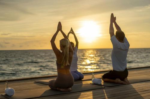 a group of people doing yoga on the deck of a cruise ship at JW Marriott Maldives Kaafu Atoll Island Resort in Male City