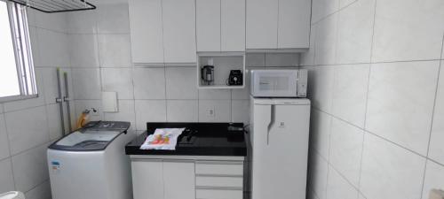 a white kitchen with a stove and a refrigerator at Apto 2 quarto completo com vaga-proximo shopping contagem in Contagem