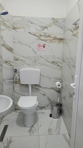 a white bathroom with a toilet and a sink at Guesthouse NA in Durrës
