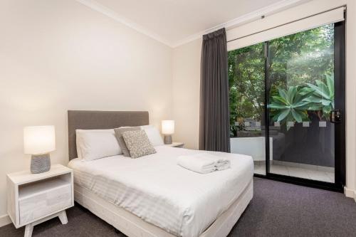 a bedroom with a white bed and a large window at Subiaco Rooftop on Sheen in Perth