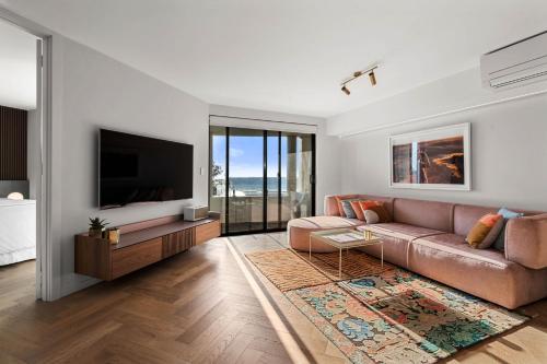 a living room with a couch and a flat screen tv at Cottesloe Neue Blue Apartment in Perth