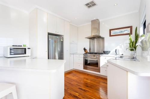 a kitchen with white cabinets and a stainless steel refrigerator at Scarborough Villa on Mickey in Perth