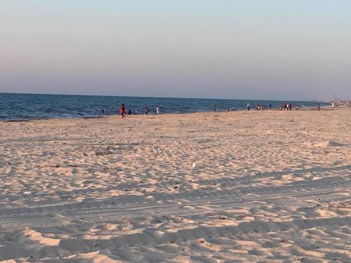 a group of people walking on the beach at فيلا مستقلة بحديقة خاصة بالساحل الشمالى in Dawwār Abū Maḩrūs