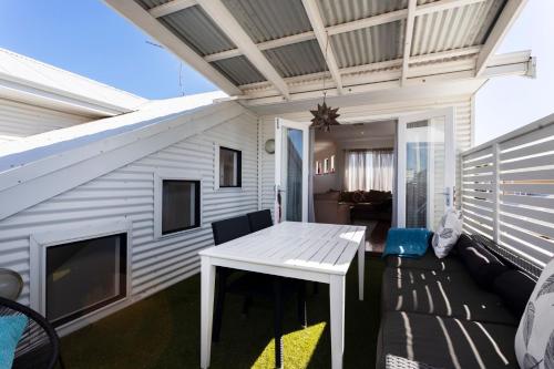 a patio with a white table and a couch at Scarborough Villa on Mickey in Perth