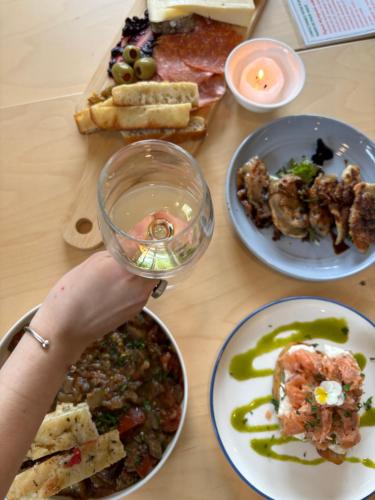a table with plates of food and a person holding a wine glass at Auberge du Jardin in Petit-Saguenay