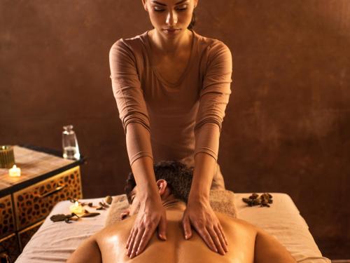 a woman sitting on a bed with a woman getting a massage at Tombo Beach in Guarujá