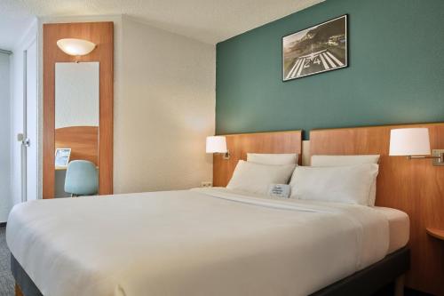 a hotel room with a large bed with white pillows at Kyriad Paris Sud Les Ulis Courtaboeuf in Les Ulis
