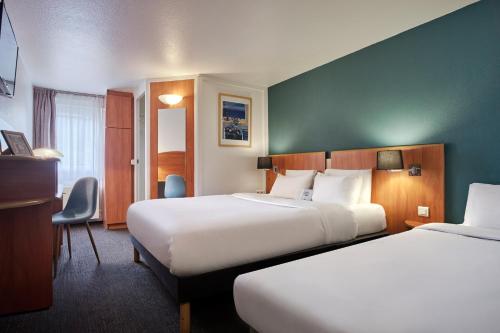 a hotel room with two beds and a desk at Kyriad Paris Sud Les Ulis Courtaboeuf in Les Ulis