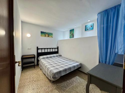Schlafzimmer mit einem Bett und einem Tisch sowie blauen Vorhängen in der Unterkunft Casa con vistas al mar y piscina privada in Lloret de Mar
