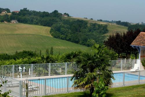a white fence around a swimming pool next to a field at Domaine Garmidou in Lucq-de-Béarn