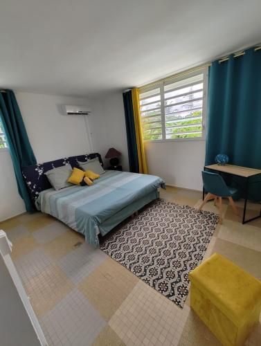 a bedroom with a bed and a table and window at Appartement F3 Caracosy tout confort in Les Abymes