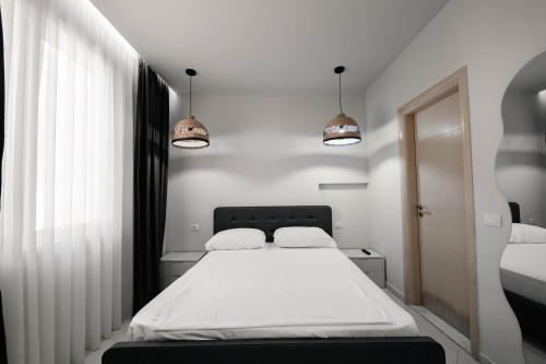 a bedroom with a white bed and two lights at Hotel Ble Ble Vlore in Vlorë