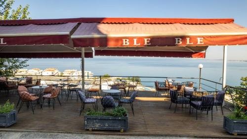 a restaurant with tables and chairs on a deck at Hotel Ble Ble Vlore in Vlorë