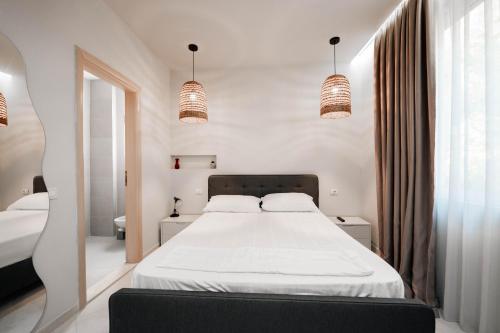 a bedroom with a large bed with white sheets and lights at Hotel Ble Ble Vlore in Vlorë