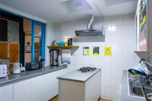 a kitchen with a stove and a white tiled wall at Hostal Providencia in Santiago