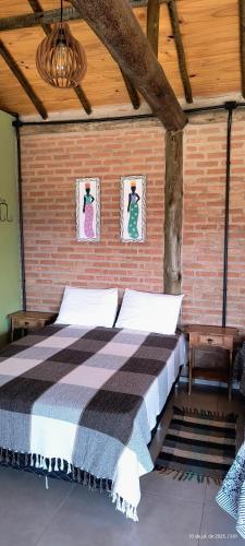a bedroom with a bed in a brick wall at Chalé estrela do cruzeiro in São Thomé das Letras