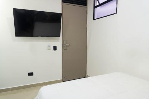 a bedroom with a bed and a tv on a wall at ApartaHotel Estadio in Medellín