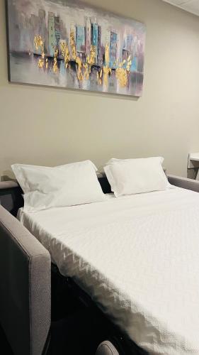 a bed with white sheets and a painting on the wall at Estremoz Hotel in Estremoz