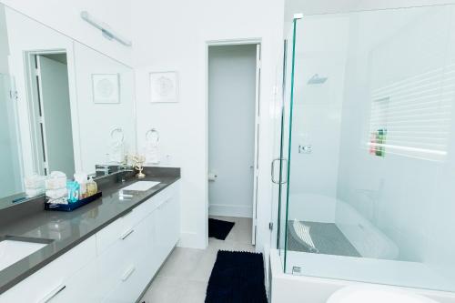 a white bathroom with a shower and a sink at Cozy and Chic 3BR Retreat in Downtown Houston in Houston