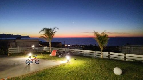 a bike parked on a sidewalk next to the ocean at night at Villa Mare Luna in Balestrate