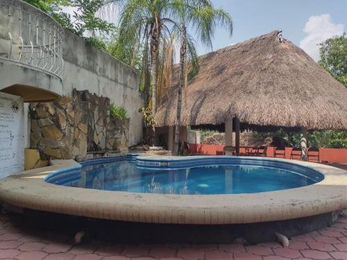 a swimming pool at a resort with a thatch roof at Hotel Tamazunchale in Tamazunchale