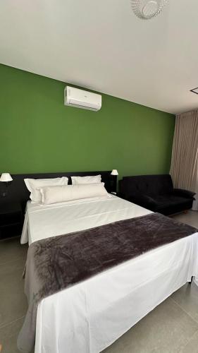 a bedroom with a large bed and a green wall at Pousada Flor de Piri in Pirenópolis