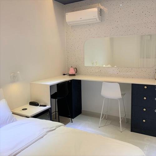 a bedroom with a desk with a white bed and a white bedskirts at No 25 Hotel Dongseongro branch in Daegu