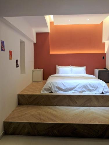 a bedroom with a large bed with an orange wall at No 25 Hotel Dongseongro branch in Daegu