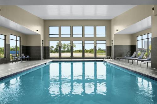 a swimming pool with blue water in a building with windows at Residence Inn by Marriott Indianapolis Noblesville in Noblesville