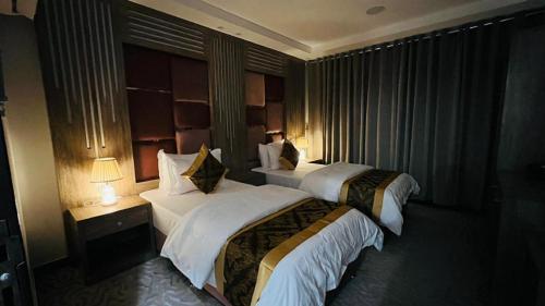 Una habitación de hotel con dos camas y dos lámparas. en شقق العزيزية إن للشقق المخدومة, en Najrán