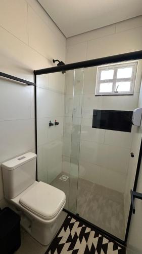 a bathroom with a toilet and a glass shower at Pousada Flor de Piri in Pirenópolis