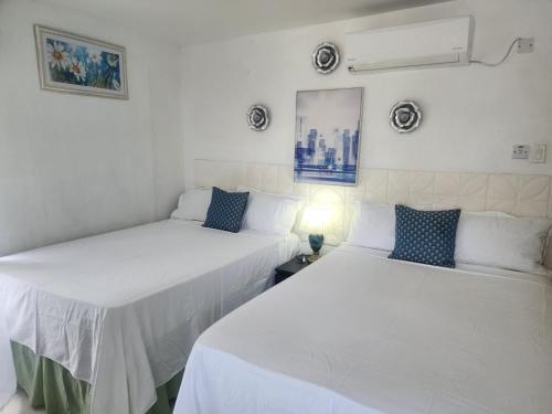 two beds in a room with white walls at Pearl of The City BLUE PEARL in Kingston
