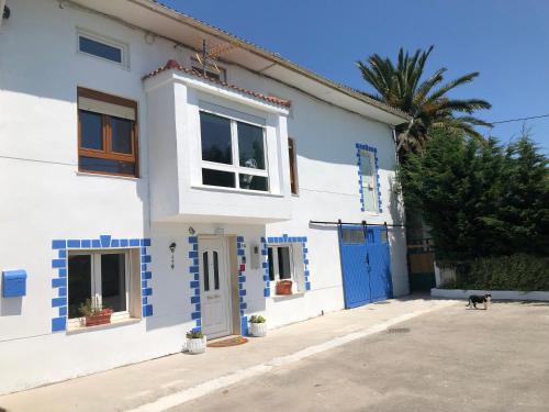 a blue and white house with a dog standing outside at Alojamiento Costa Quebrada in Soto de la Marina