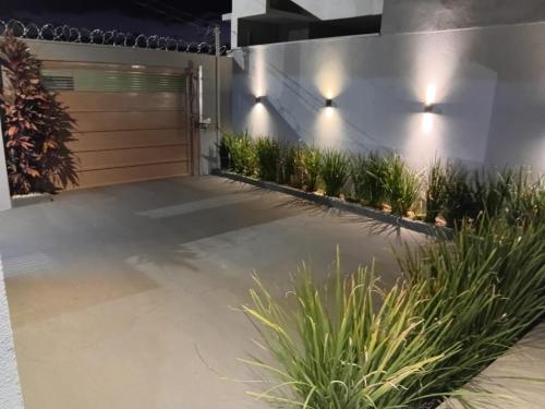 a driveway with a garage door and plants at casa inteira com 3 suites e área de lazer in Delfinópolis