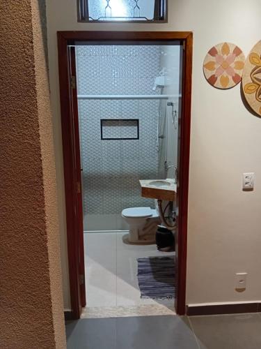 a bathroom with a toilet and a glass shower door at casa inteira com 3 suites e área de lazer in Delfinópolis