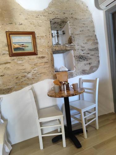 a table and chairs in a room with a stone wall at Vgena's house 2 the little house in Dhió Kkhoriá