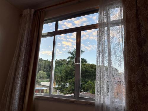 a window with a view of a tree at Apartamento completo em Caxambu in Caxambu