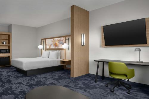 a hotel room with a bed and a desk and a tv at Fairfield by Marriott Inn & Suites Sikeston in Sikeston
