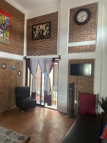 a living room with a chair and a clock on the wall at Beatiful aparment in the magical town of Orizaba 2 in Orizaba