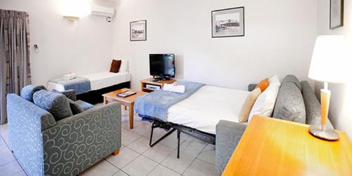 a room with a bed and two chairs and a tv at Trinity Beach Pacific in Trinity Beach