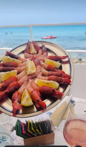a plate of shrimp and lemons on a table at the beach at Hotel Miramare in Gallipoli