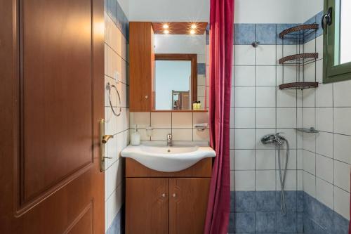 a bathroom with a sink and a red shower curtain at Orianthi's Beachfront Home in Skala Kefalonias