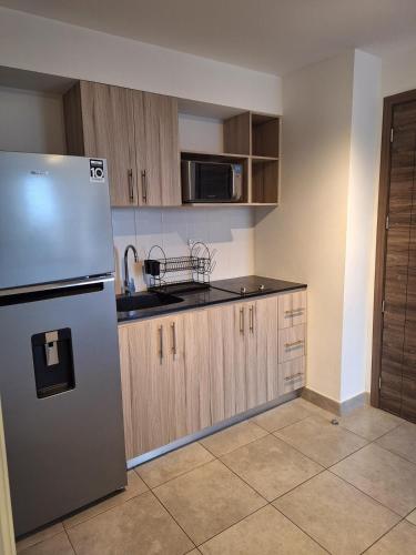 a kitchen with a stainless steel refrigerator and wooden cabinets at En plena ciudad de Guatemala in Guatemala