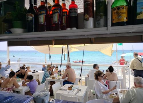 a group of people sitting at tables on the beach at Hotel Miramare in Gallipoli
